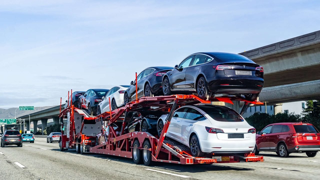 Open car carrier trailer stacked with cars on an open road